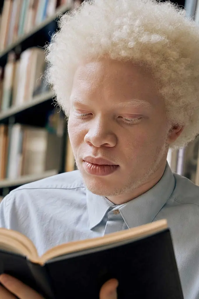 Personne avec albinisme lisant dans une bibliothèque