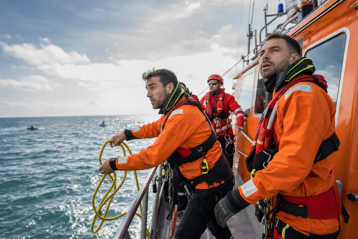 Sauveteurs en mer en tenue orange et rouge à bord d'une vedette de sauvetage en pleine mer